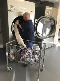 mann legger tøy i vaskemaskin